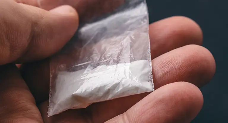Man holding dime bag of cocaine